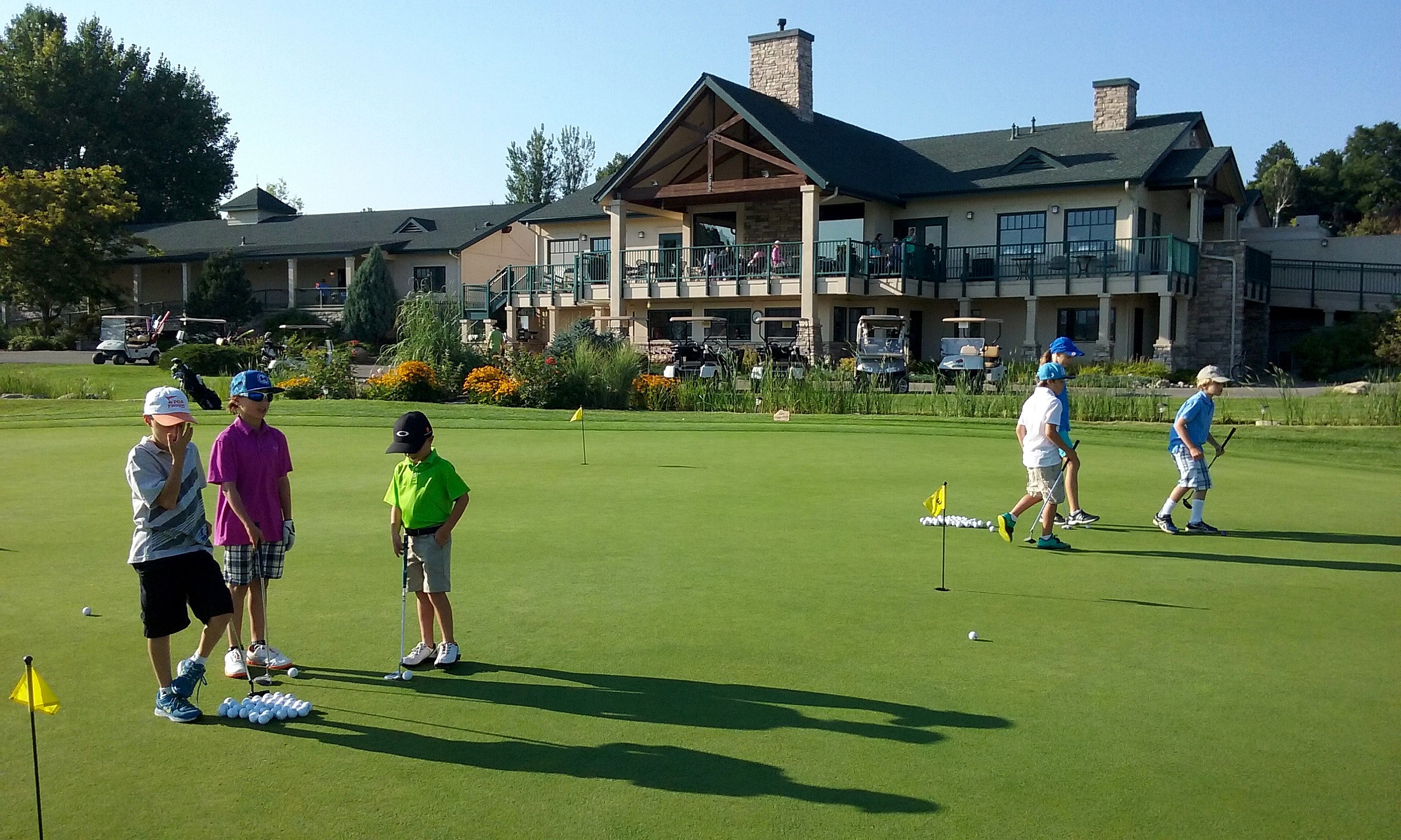 Youth golfers practicing on Lake Valley's large putting green with clubhouse visible
